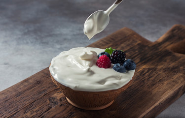 Greek yogurt in a wooden bowl on a rustic wooden table.