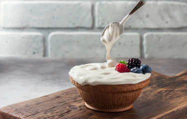 Greek yogurt in a wooden bowl on a rustic wooden table.