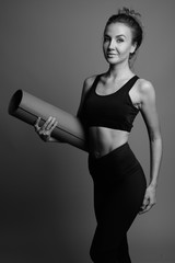 Young beautiful woman ready for gym against gray background