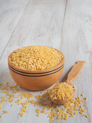 Orzo (risoni) pasta in wooden bowl. 