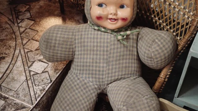 Old creepy baby doll seated on a rocking chair made of wood. 4k