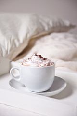 Cup of cappuccino on the white tray on the bed early morning