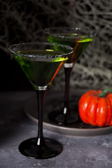 Two glasses with green zombie cocktail for Halloween party on the dark background