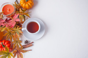 Cup of tea, autumn leaves, candle, pumpkin on the white background. Autumn harvest. Autumn concept. Top view. Copy space