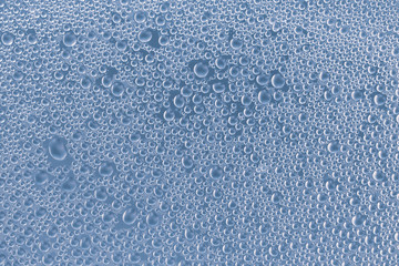 Water drops on blue background, glass. Abstract gray backdrop of foam bubbles. Bubble pattern. Transparent condensation, modern design.