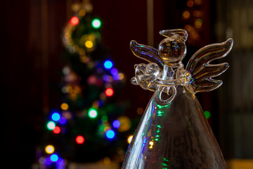 transparent glass angel on a background of light bulbs from a garland
