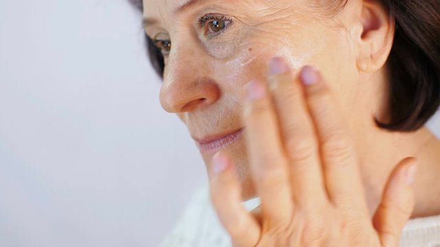 Woman applying cream on face