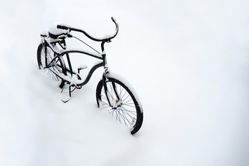 Bicycle covered in snow. Bicycle parked in snow. Bike buried in snow. Bike outdoors covered with a lot of snow, bad weather conditions. copy space. Road safety. Life insurance concept