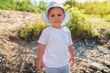 Portrait of small little boy child by the river in sunny day