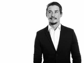 Studio shot of young happy businessman smiling while thinking isolated against white background