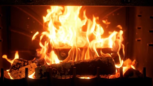 Slow motion video of burning wooden logs in fireplace. Slowmo of fire flames and rising smoke