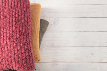 stack of sweaters on  white wooden table
