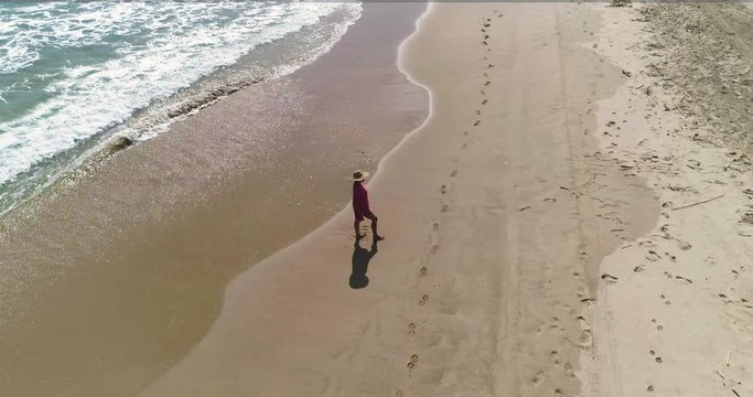 Mujer con pamela mirando el horizonte en una playa y dron girando sobre ella