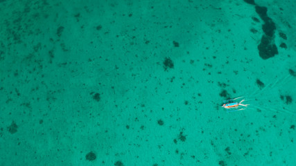 Tourist motor boat on the surface of turquoise water in tropical lagoon, aerial view. Seascape with beach on tropical island. Summer and travel vacation concept. Boracay Island, Philippines