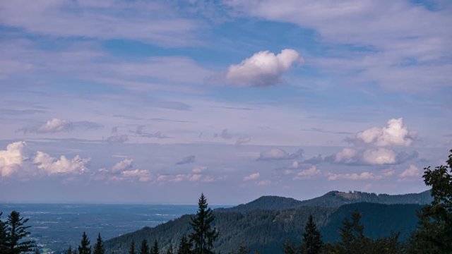 Zeitraffer Bayerische Voralpen von der Benediktenwand ins Voralpenland bis M&uuml;nchen am Horizont mit ziehenden wei&szlig;en Wolken bei blauem Himmel