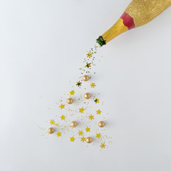 Creative Christmas or New Year background. Champagne bottle with gold glitter Christmas tree. Minimal flat layt concept.