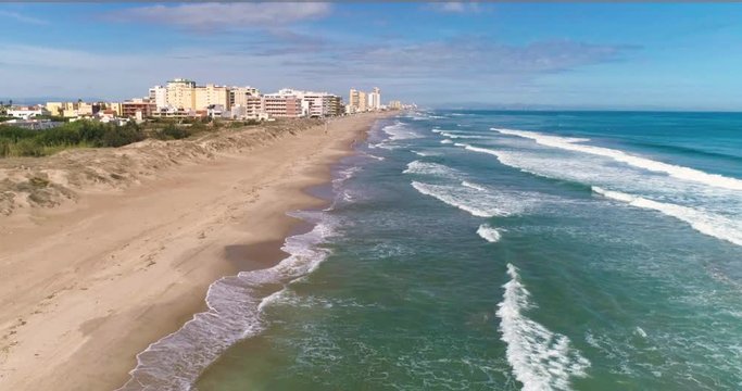 Dron vuela playa amplia junto a ciudad costera a vista de p&aacute;jaro