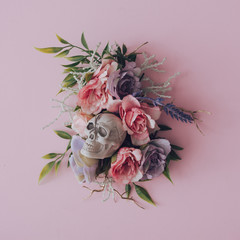 Creative floral layout with skull and roses on pastel pink background. Spooky nature flat lay.