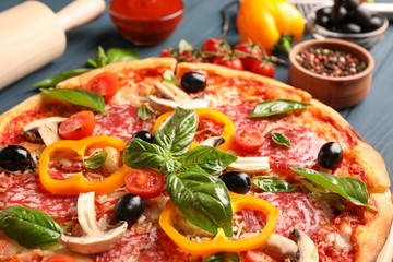 Delicious pizza and ingredients on wooden background, close up