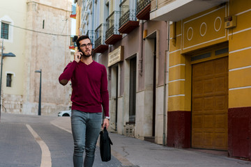 Fototapeta na wymiar Young businessman is walking on the street while he is talking with his phone