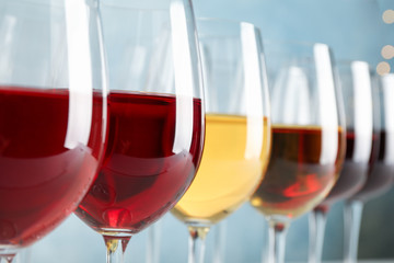 Glasses with wine against light blue background, blurred lights, closeup