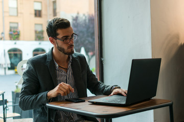 Young businessman in a pub working with his laptop