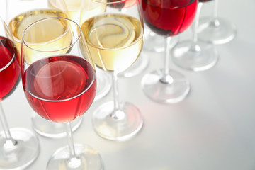 Glasses with different wine on white background, close up