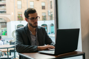 Young businessman in a pub working with his laptop
