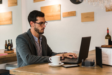 Young businessman in a pub working with his laptop