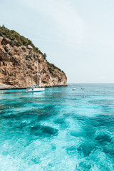 Fototapeta premium Boat floating in crystal clear water in Sardinia, Italy