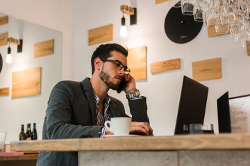 Young businessman in a pub working with his laptop