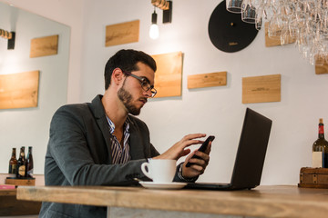Young businessman in a pub working with his laptop