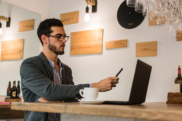 Young businessman in a pub working with his laptop