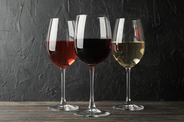 Glasses with different wine on wooden background, space for text