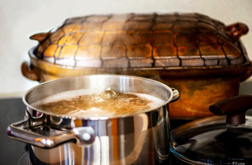 Pot with bubbling broth, old rustic pan on stove.