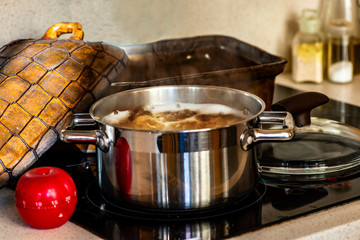 Steel pot with boiling broth,pan, red apple kitchen timer.