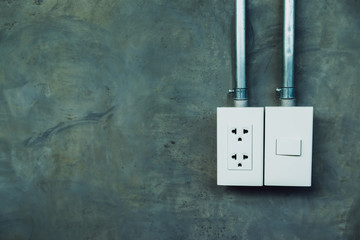 Electric light switch and plug socket on the cement wall