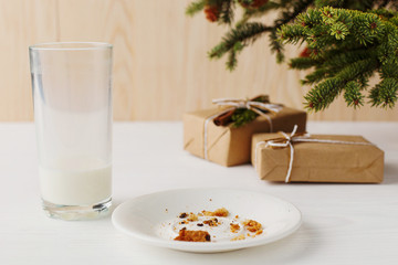 Empty glass of milk and crumb biscuits and a gift under the Christmas tree. The concept of the arrival of Santa Claus.