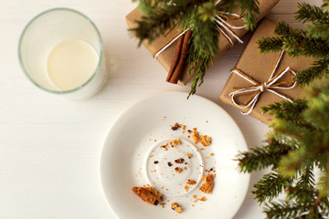 Empty glass of milk and crumb biscuits and a gift under the Christmas tree. The concept of the arrival of Santa Claus.