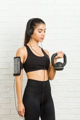 Fototapeta na wymiar Young arab sporty woman listening to music and holding a dumbbell