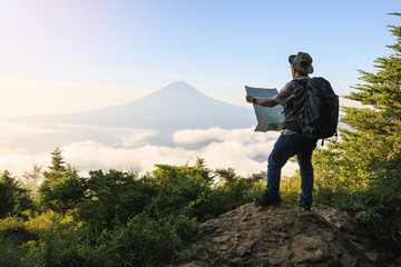 Young Asian tourist trekking to the top and checking map for seeing Mount Fuji in Japan summer...