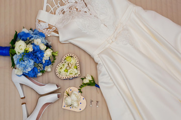 wedding rings, shoes and dress of the bride on the bed