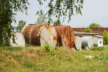 Obraz premium Old rusty fuel tanks in the yard. Clear sunny summer day