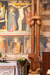 Fototapeta premium Strange knot on marble pillar in front of religious ancient frescoes inside catholic church in Verona