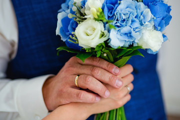 Obraz na płótnie Canvas wedding bouquet in blue in the hands of the bride and groom