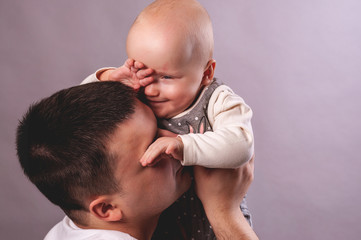 One year old daughter in her father's arms. Dad plays with baby, nurses her.