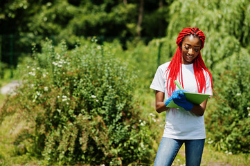 African red haired volunteer woman with clipboard in park. Africa volunteering, charity, people and ecology concept.