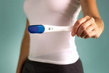 The girl holds in her hand a positive pregnancy test. The beginning of pregnancy. Pregnancy proof....