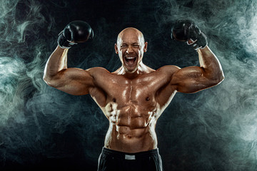 Sportsman, man boxer fighting in gloves on black background and celebraiting victory. Fitness and boxing concept.