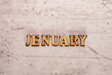 The word Jenuary laid out in wooden letters on a light background. Close-up. Summer time years and months of the year.